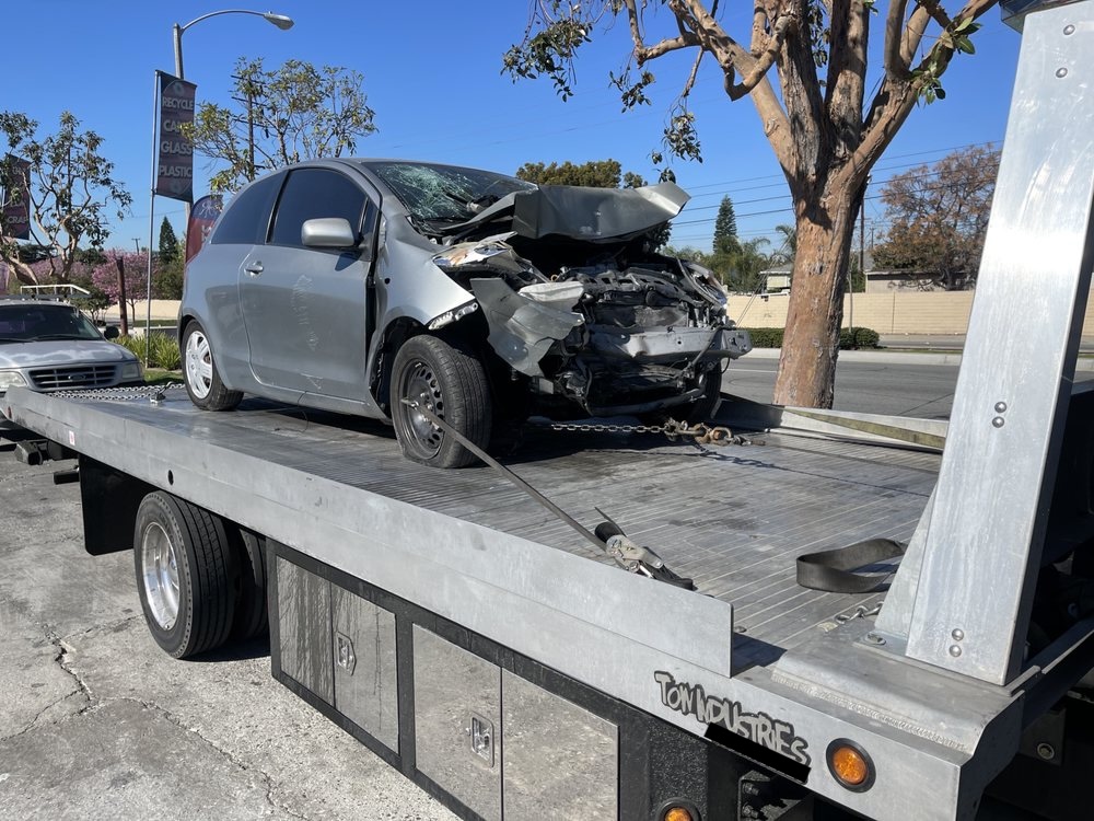 Accident-damaged car recovered on a flatbed tow truck