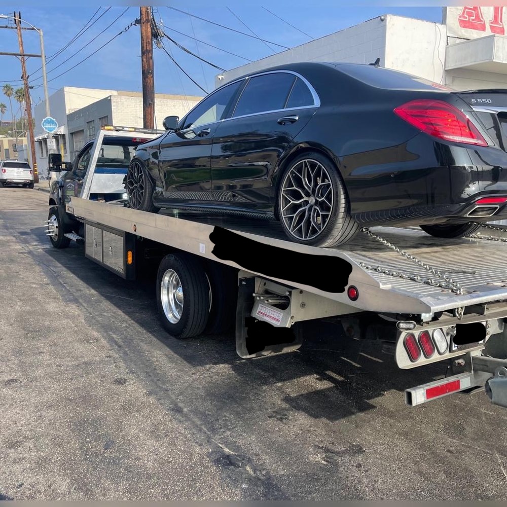 Sedan loaded and secured on a flatbed tow truck