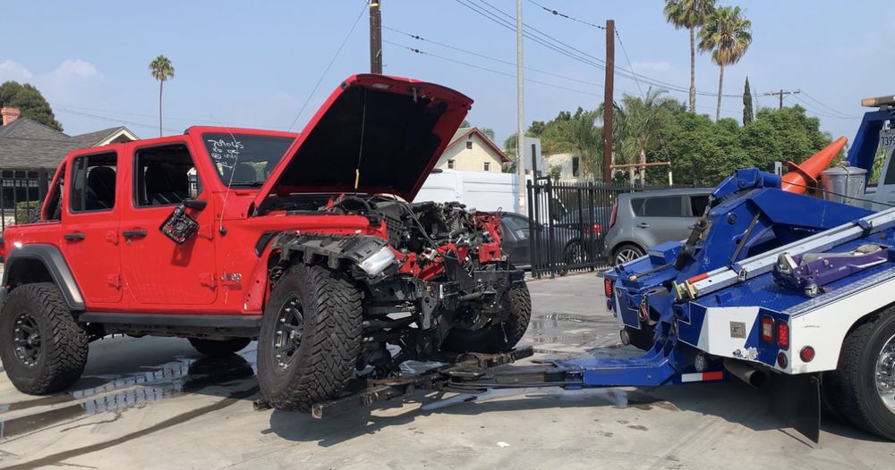 Jeep with the hood up being loaded after a breakdown