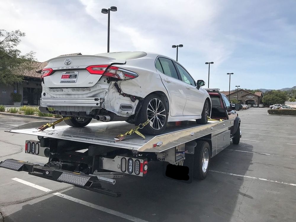 White car secured on a flatbed tow truck deck